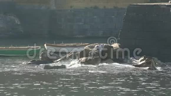 木船漂浮在城堡的底部海浪拍打着石头视频的预览图