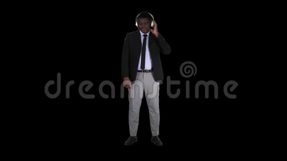 戴着耳机的英俊的美国黑人商人正在听音乐阿尔法频道视频的预览图