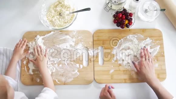 妈妈和女儿用手把面粉洒在木板上准备薄煎饼视频的预览图