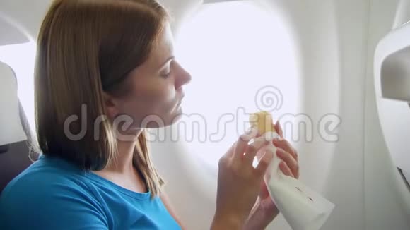 白天坐飞机的女人在湍流中饥饿的女性在靠近窗户的地方吃三明治视频的预览图