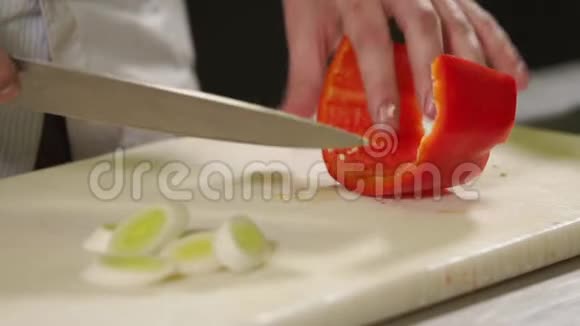 厨师正在厨房桌子上的木板上切一个红甜椒特写视频的预览图