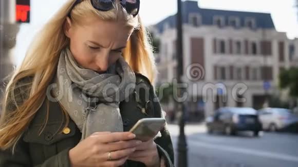户外使用电话的年轻女人的肖像在阳光明媚的日子里一个严肃美丽的年轻女人在打电话视频的预览图