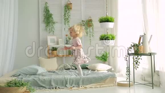 小女孩在明亮的房间里跳床里面有绿色的植物视频的预览图
