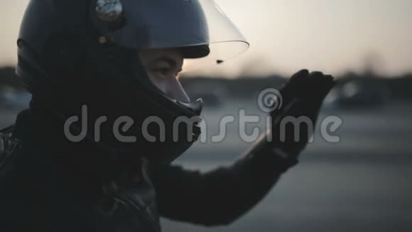 街头戴着黑色头盔的年轻漂亮摩托车手的肖像骑摩托车的人视频的预览图