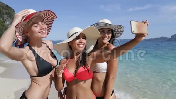 女孩在海滩上的手机上自拍在度假的年轻游客团体中快乐微笑的女性视频的预览图