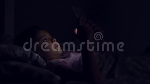 一个漂亮的小女孩晚上用她的平板电脑视频的预览图