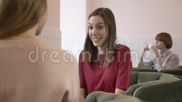 三个白种人年轻女孩坐在咖啡馆里微笑着说话对话惊讶笑流言蜚语视频的预览图