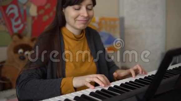 一个年轻的女人玩电子合成器她的手触摸钥匙视频的预览图