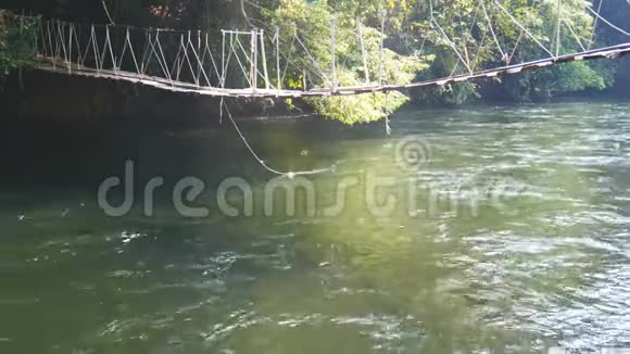 4K用老木板做成的吊桥穿过一条小河早晨阳光明媚溪水潺潺视频的预览图