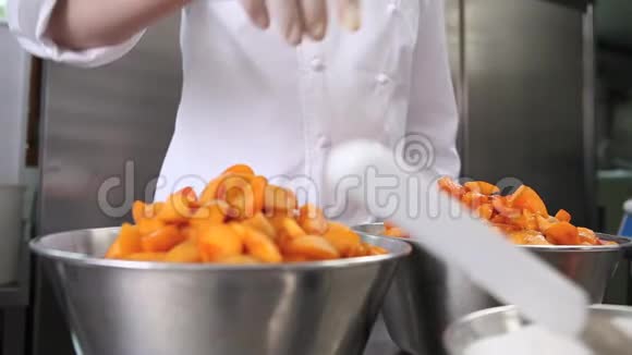 手把糕点厨师把糖铺在杏子水果上在工业厨房准备果酱视频的预览图