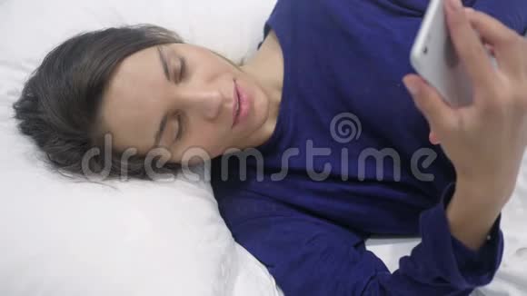 在床上的西班牙裔妇女在线视频聊天视频的预览图
