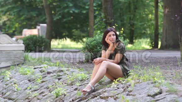 一个女孩坐在公园的岩石上视频的预览图