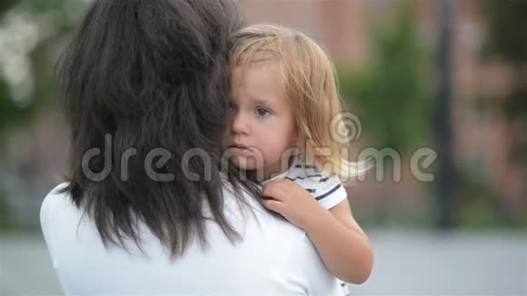 一个悲伤的女儿拥抱母亲的户外布鲁内特妈妈与她的孩子小女孩与沮丧的脸视频的预览图