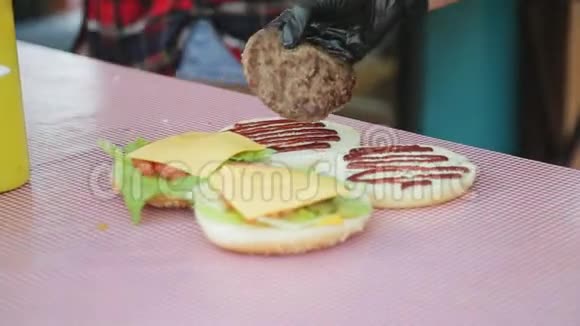 厨师的手在汉堡的小面包上放炸片视频的预览图