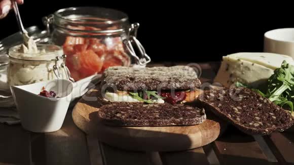 女性手工制作三明治与鹰嘴豆泥和鲑鱼作为早餐特写镜头晴天视频的预览图