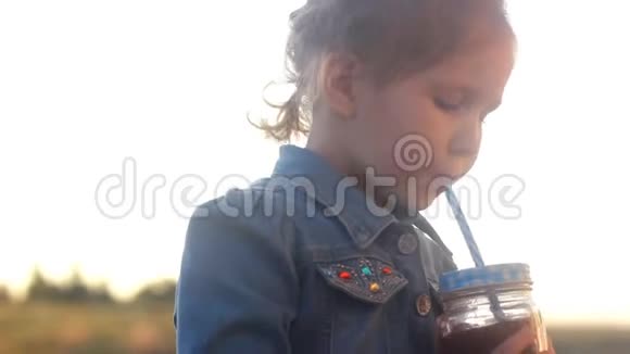 小女孩喝鸡尾酒果汁冰沙夏日日落时的肖像特写视频的预览图
