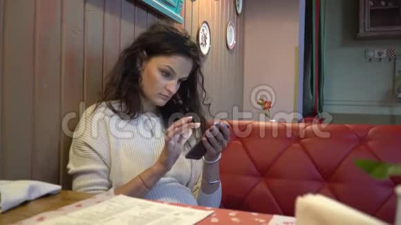 在咖啡馆里使用智能手机的女人视频的预览图