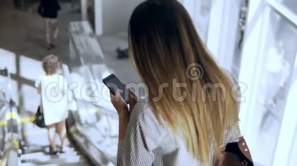 在现代办公楼工作的年轻女商人忙碌的女性坐自动扶梯使用智能手机视频的预览图