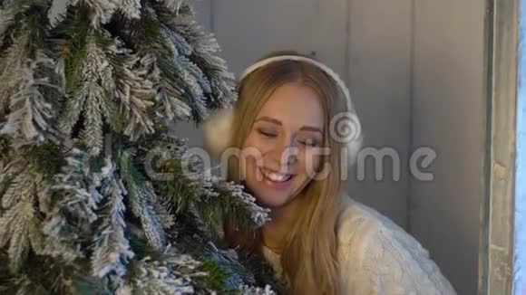一位美丽的年轻女子在假日室内的圣诞树下摆姿势视频的预览图
