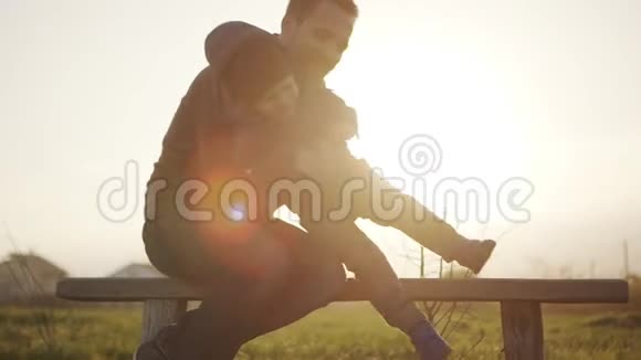 索洛莫父亲高兴地抱着小儿子坐在长凳上在日出的时候关门概念视频的预览图