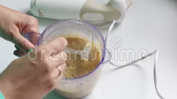 女人打开搅拌机与粉碎的蔬菜团并与勺子混合视频的预览图