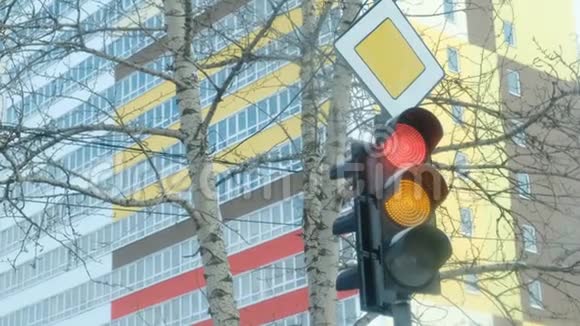 在一栋多层建筑的背景上交通灯从红色切换到黄色和绿色视频的预览图