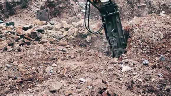 关闭一个重型建筑行业挖掘机在一个建筑工地的石头破碎视频的预览图