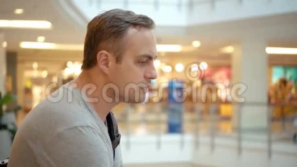 年轻的帅哥穿着灰色的t恤站在购物中心购物消费主义概念视频的预览图