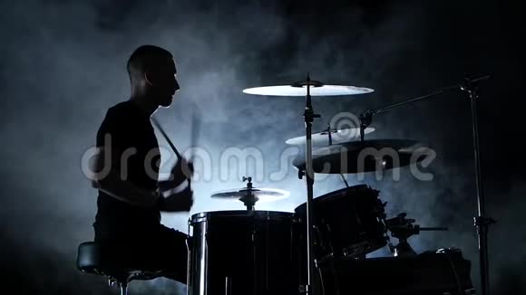 精力充沛的音乐家在鼓上演奏好音乐黑色烟熏背景侧视剪影慢动作视频的预览图
