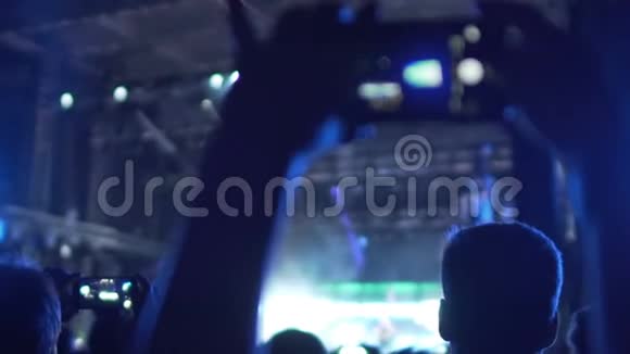 乐迷在音乐音乐会上拍摄视频欣赏喜爱的乐队表演视频的预览图