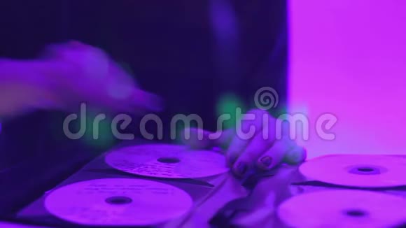 女子DJ从唱片集中取唱片在夜总会演奏音乐混音视频的预览图
