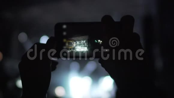 在智能手机摄像头上现场拍摄心爱摇滚乐队表演的人视频的预览图