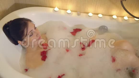 美丽的女人用泡沫和玫瑰花瓣洗澡视频的预览图