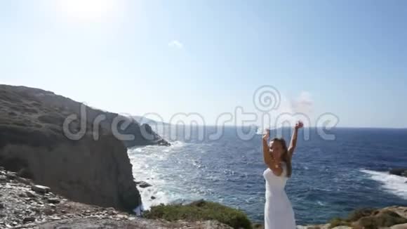 一位快乐的新娘站在海边戴着一层在风中飘扬的婚纱幸福婚姻的概念视频的预览图