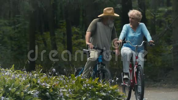 两个骑自行车的退休老人正在公园里谈话视频的预览图