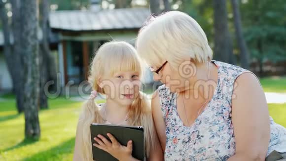 外婆和孙女正在家后院休息他们一起看着碑交流视频的预览图
