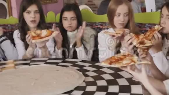 漂亮的年轻女孩吃披萨在咖啡馆里找乐子4K视频的预览图