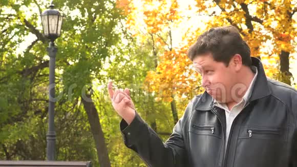 秋天公园里一个微笑的胖子用手指向我们展示更近的姿态视频的预览图