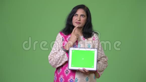 成熟美丽的印度女人一边思考一边展示数字平板电脑视频的预览图