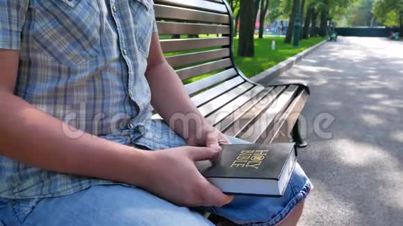夏天阳光明媚的一天人们手里拿着圣经坐在公园的长凳上视频的预览图