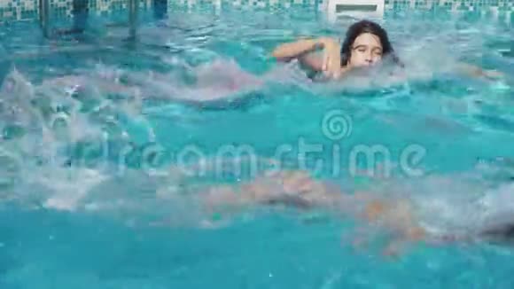 两个快乐的青少年一个兄妹正在游泳池里游泳慢动作稳定射击4k视频的预览图