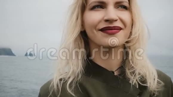年轻快乐的女人站在冰岛的海岸上享受眼前的景色巨魔脚趾悬崖视频的预览图