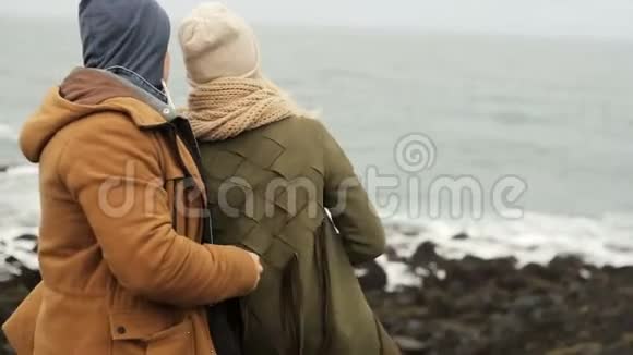 后景年轻美丽的夫妇站在海边一起欣赏风景视频的预览图