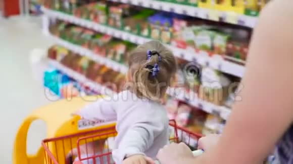 两个孩子在塑料购物车内市场与妈妈特写视频的预览图