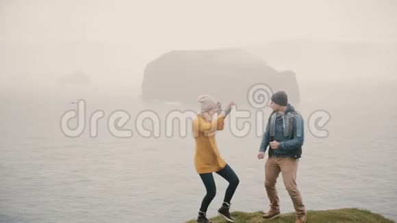 年轻的游客男女站在山的边缘跳舞一起玩的游客视频的预览图