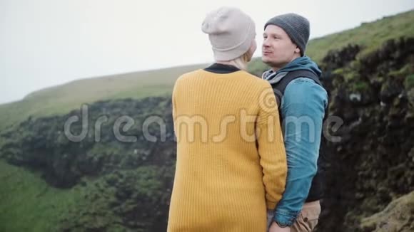 年轻漂亮的夫妇站在山上聊天接吻旅游男女探索自然视频的预览图