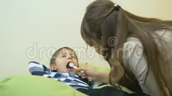 小女孩拿着玩具药器看着男孩的嘴视频的预览图