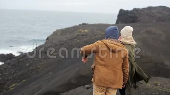 年轻时尚的夫妇站在悬崖上欣赏海景男人指着什么女人看着视频的预览图