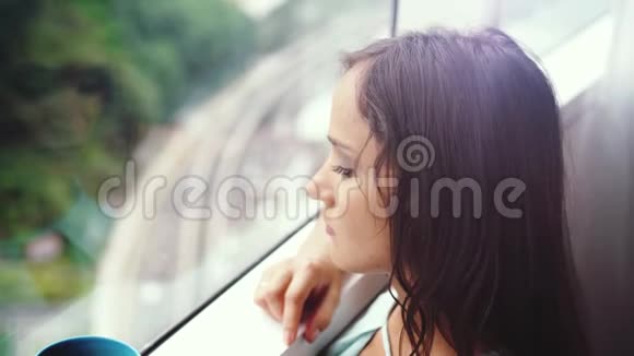 美丽的年轻黑发女人喝咖啡在全景窗口与惊人的城市景色慢动作3840x2160视频的预览图