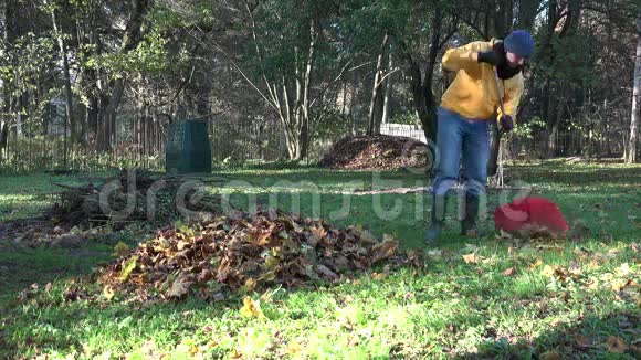 园丁在温暖的衣服准备秋叶形成堆肥在后院4K视频的预览图